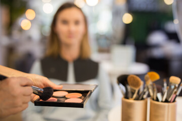 Closeup of hands of makeup artist holding professional cosmetic dry tonal foundation palette and...