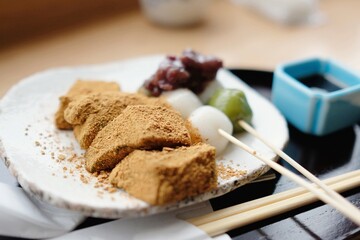 A plate of assorted traditional Japanese rice cake desserts: dango skewers topped with adzuki (red bean) paste and bean powder-coated warabi mochi at Tsujiri, Tokyo Station (Daimyo Department Store)