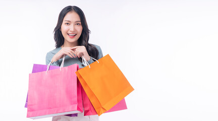 Fototapeta na wymiar Enjoyment excited asian woman carry shopping bags standing on white background. Trendy happy shopper consumer carefree young girl holding shopping paper bags with copy space over isolated background.