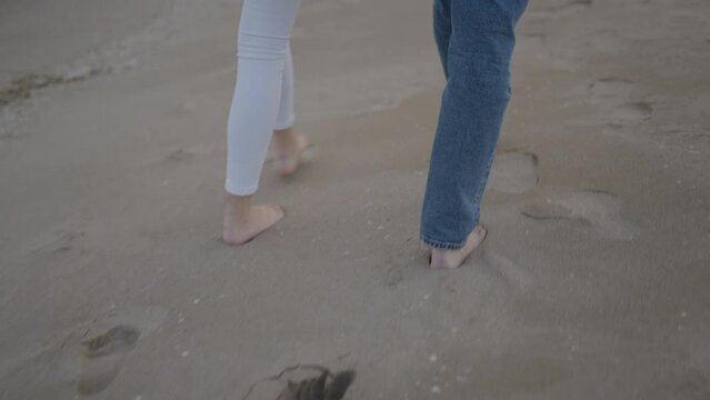 Couple walks coordinated leaving their footprints behind at the beach sand 