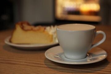Cup of aromatic coffee and delicious dessert on wooden table in cafe, closeup