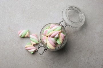 Glass jar with delicious colorful marshmallows on light grey table, flat lay