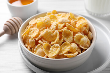 Bowl of tasty crispy corn flakes on white wooden table, closeup