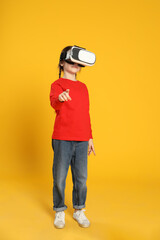 Little girl using virtual reality headset on yellow background