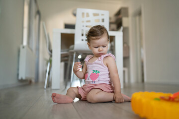 One toddler sitting on the floor eating and looking down Early child development learning and playing concept