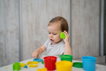 One girl small caucasian toddler child playing with colorful plasticine on the table at home alone childhood and growing up development concept copy space