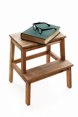 Vintage Book and Glasses are Laying on Wooden Stool