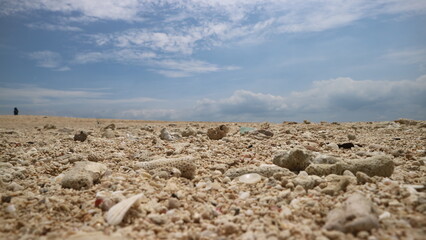 Sand and rocks by the beach against a backdrop of blue sky and soft white clouds. great for backgrounds and wallpapers