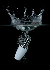 Glass bottle of anti aging serum splashing into water on black background,Cosmetic for skin care