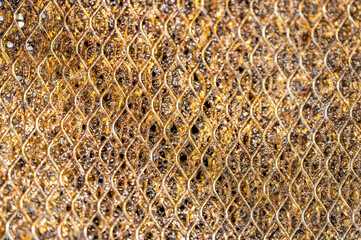 Selective focus macro of a dirty kitchen range hood filter clogged with grease.