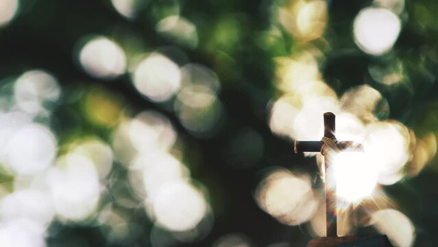 The cross of Jesus Christ shining through the trees and the sunlight shining through the leaves and beautiful ray of light bokeh
