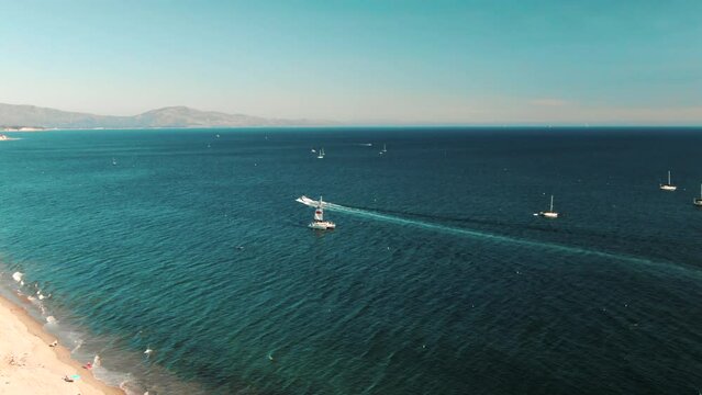 Drone Aerial shot of ocean, yacht, boat. Waves foaming on golden sand beach. Beautiful nature background. Coastline. Summer vacation at sea. High quality 4k slow motion footage.