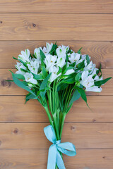 Bouquet of white alstroemeria flowers on a white wooden background.