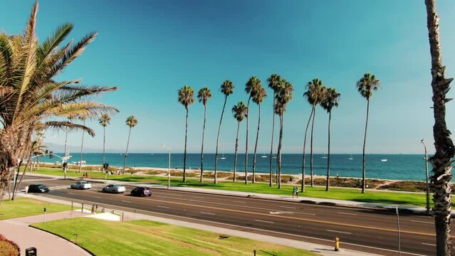 Aerial Drone view on beach coastline in Santa Barbara, Los Angeles, California, USA. Beautiful sunny day during summer. Palms and grass. People and cars on streets near ocean. High quality 4k footage