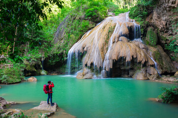 Tourists in red shirts backpacker take a photo and admiring the beauty of Koh Luang Waterfall, Lamphun, Thailand.