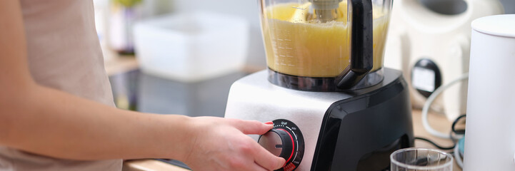 Woman cook turning on button of food processor for kneading dough closeup