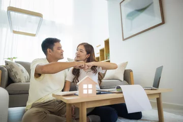 Fotobehang Asian couple in home or house. To bump punch, compare prices, interest, credit and calculate together. Include laptop, calculator and document on table. Concept for marriage, family, loan, finance.  © DifferR