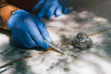 Closeup of gloved hands removing old wax with a wax comb.