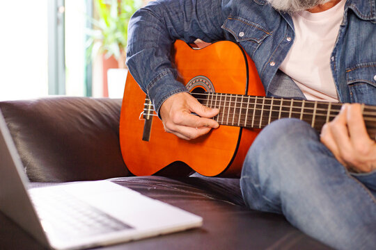 Close-up of a  man playing acoustic guitar online.