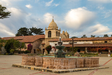 Fountain and courtyard, with blue sky and puffy white clouds,  The Carmel Mission Basilica, the...