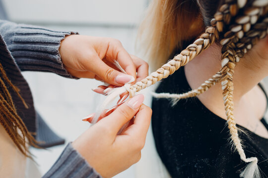 Hairstylist braiding female client's hair