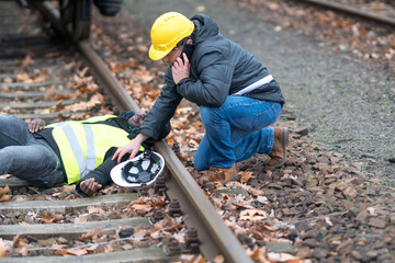 Man in black jacket and yellow hard hat standing on train rail