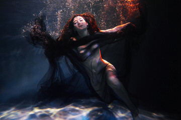 Nude woman covered with black textile under water