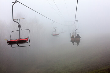 Mountain lift takes tourists to the mountain in dense fog