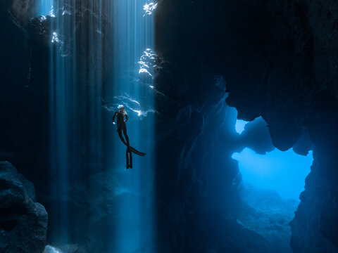 Person diving inside cave under water