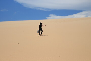 Fototapeta na wymiar Young man walking on the desert and looking for a sign LOMAS DE ARENA - SANTA CRUZ BOLIVIA