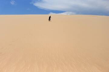 Young man walking on the sand and looking for a sign - LOMAS DE ARENA SANTA CRUZ BOLIVIA