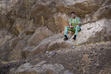 Portrait of young man sitting on rock