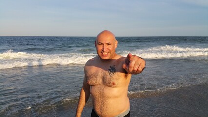 Topless man in gray shorts standing on beach