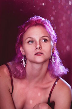 Studio Portrait Of Young Woman With Blue Eyes Against Purple Background