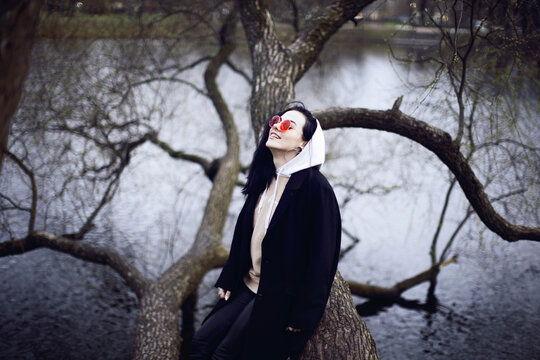 Woman in black coat sitting on tree