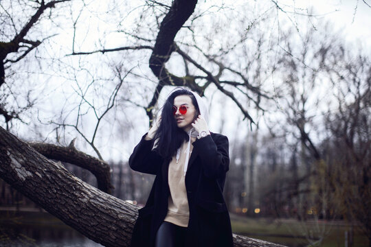 Woman in black coat standing beside brown tree