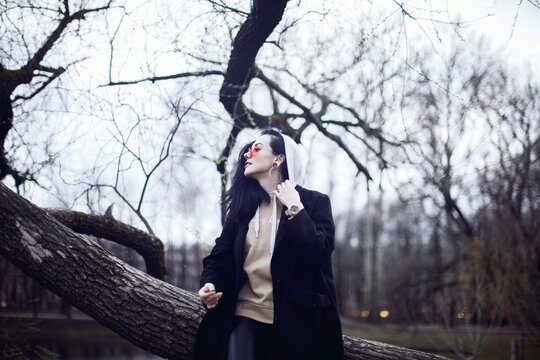 Woman in black coat standing beside tree