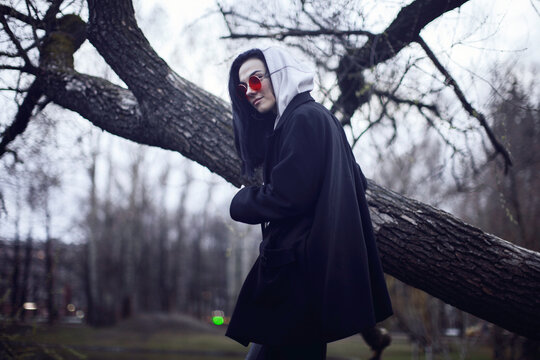 Woman in black coat standing near brown tree