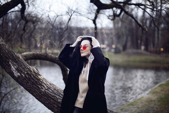 Woman in black coat standing near bare tree