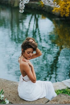 Woman in light dress sitting by pond