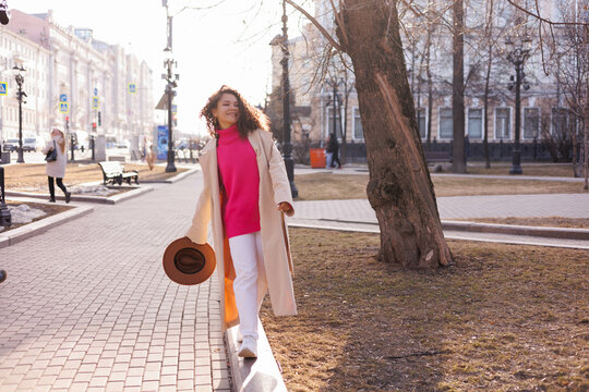 Woman in white coat standing on sidewalk