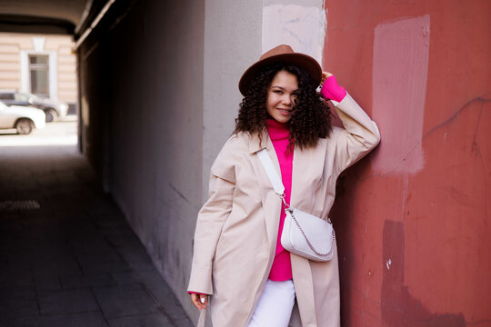 Woman In White Coat Standing Beside Red Wall