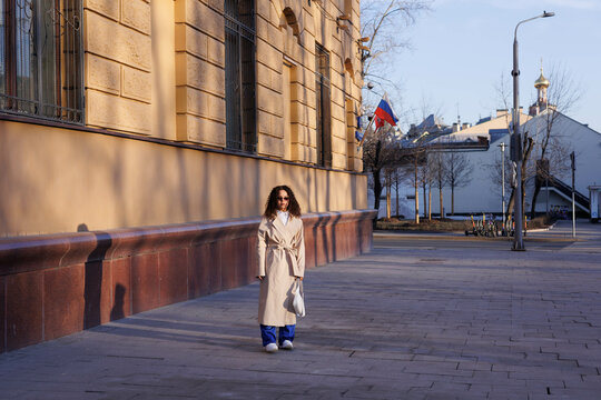 Woman in white coat standing on sidewalk