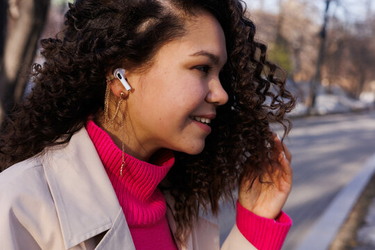 Woman In White Coat With Pink Scarf And White Earbuds