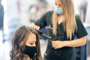 Woman with facemask getting her hair done at the beauty salon