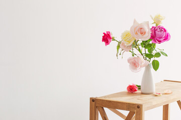 pink and white roses in white ceramic vase on white background