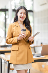 Successful Business Asian woman in Stylish Dress Using Tablet Computer, Standing in Modern Office Working on Financial, Business and Marketing Projects. Portrait of Beautiful Asian Manager.