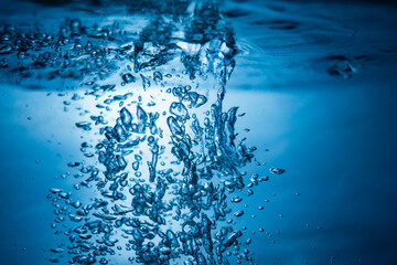 An abstract background created by air bubbles in water under blue lighting.