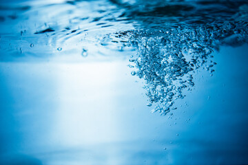 An abstract background created by air bubbles in water under blue lighting.