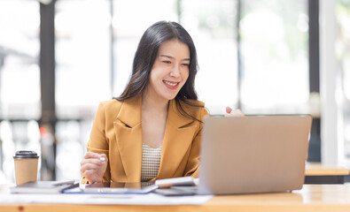 Fototapeta na wymiar Successful Business Asian woman looks surprised and excited at laptop screen, receive pleasant notification, watching on laptop computer, cellular internet, Excited happy asian woman.